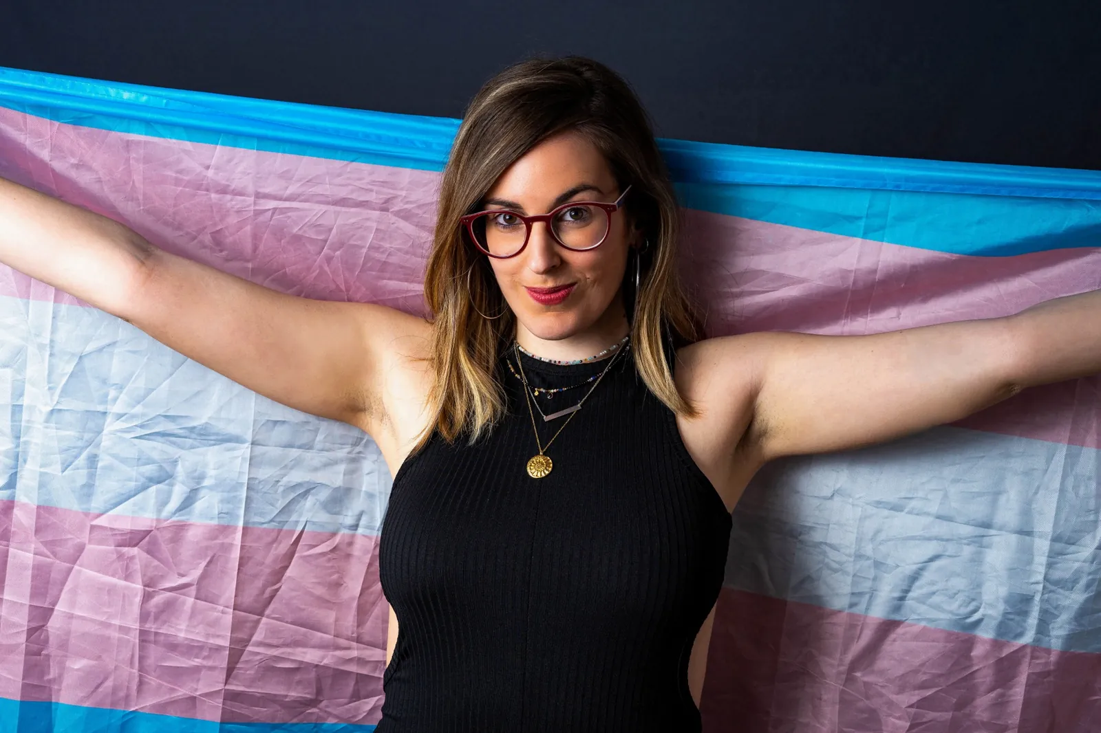 OnlyFans agency for trans creators holding a transgender pride flag, representing privacy, confidence, and growth on OnlyFans.